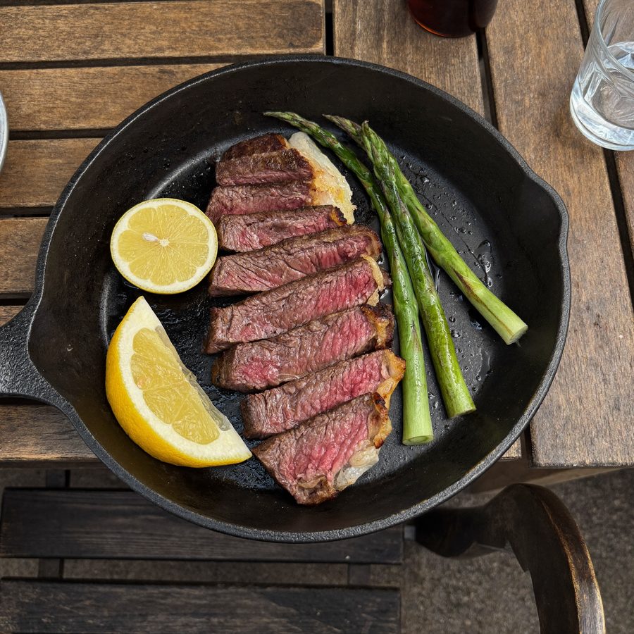Sliced steak with asparagus in a cast iron pan