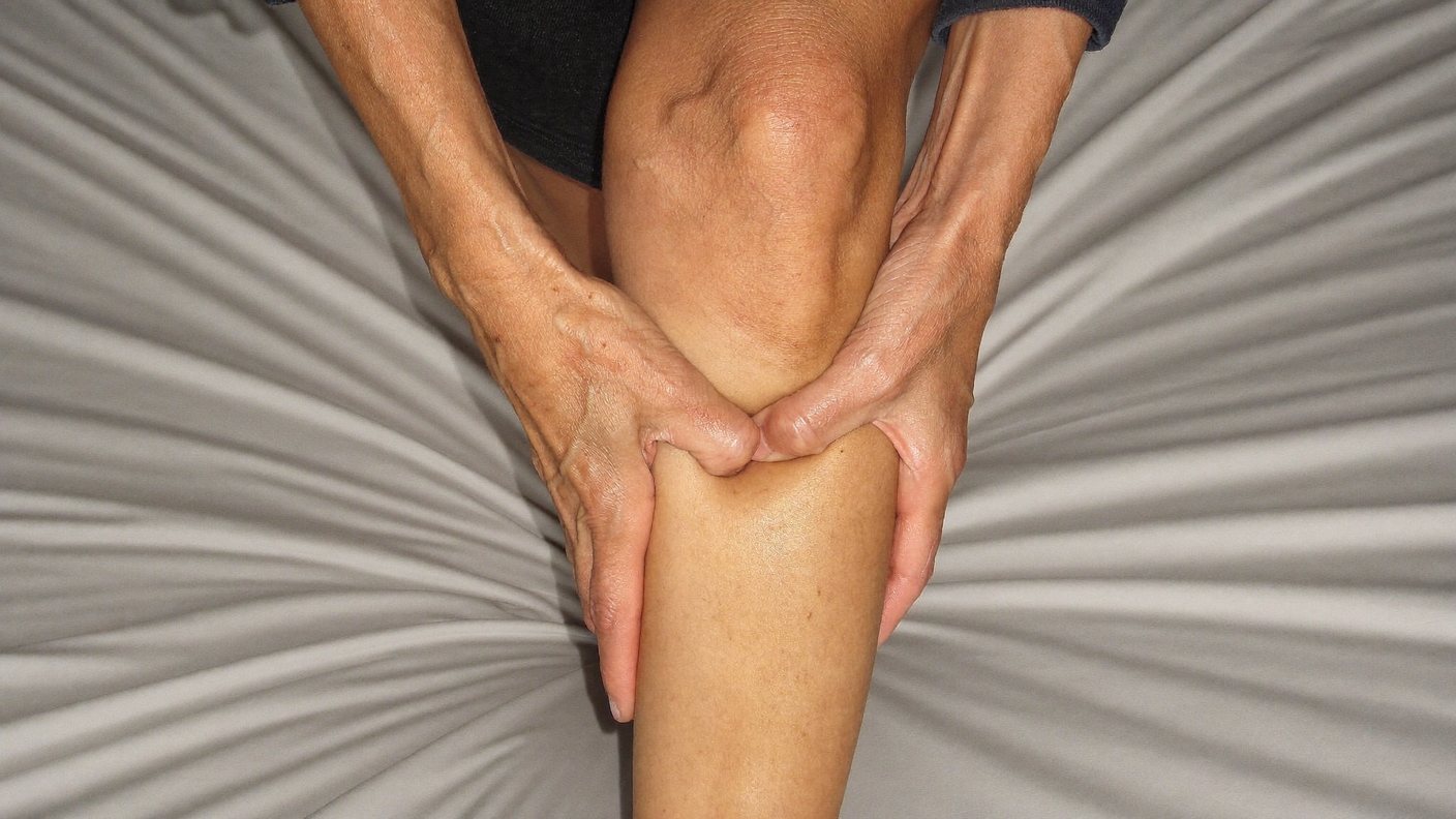 Hands gripping a calf muscle during a cramp