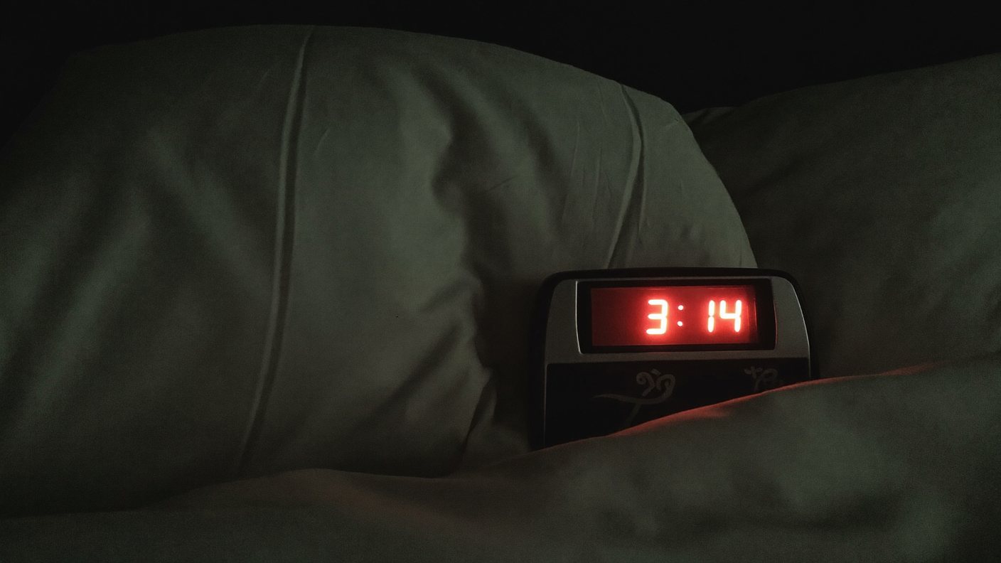 A bedside clock glowing in a dark bedroom in the middle of the night