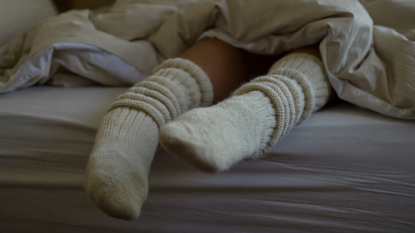 Feet in thick wool bed socks under a duvet